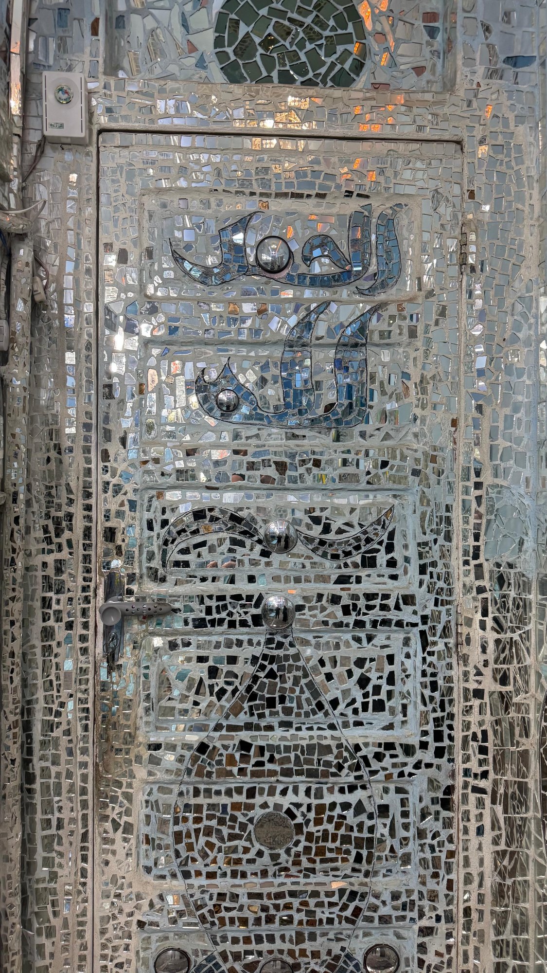بابٌ مكسوٌّ بالكامل بفسيفساء المرايا والخط العربي