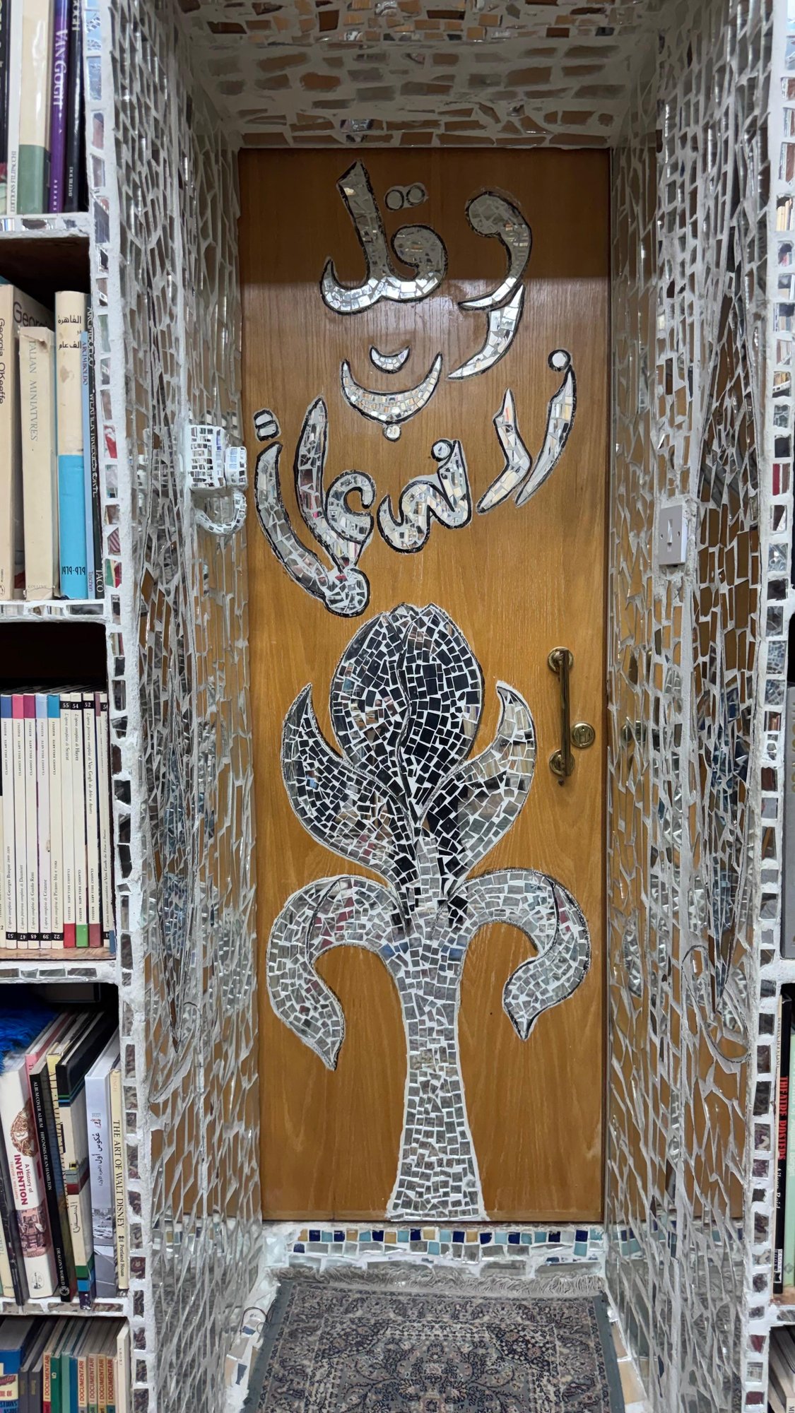 شجرة الحياة من المرايا في بابٍ خشبي بين رفوف الكتب