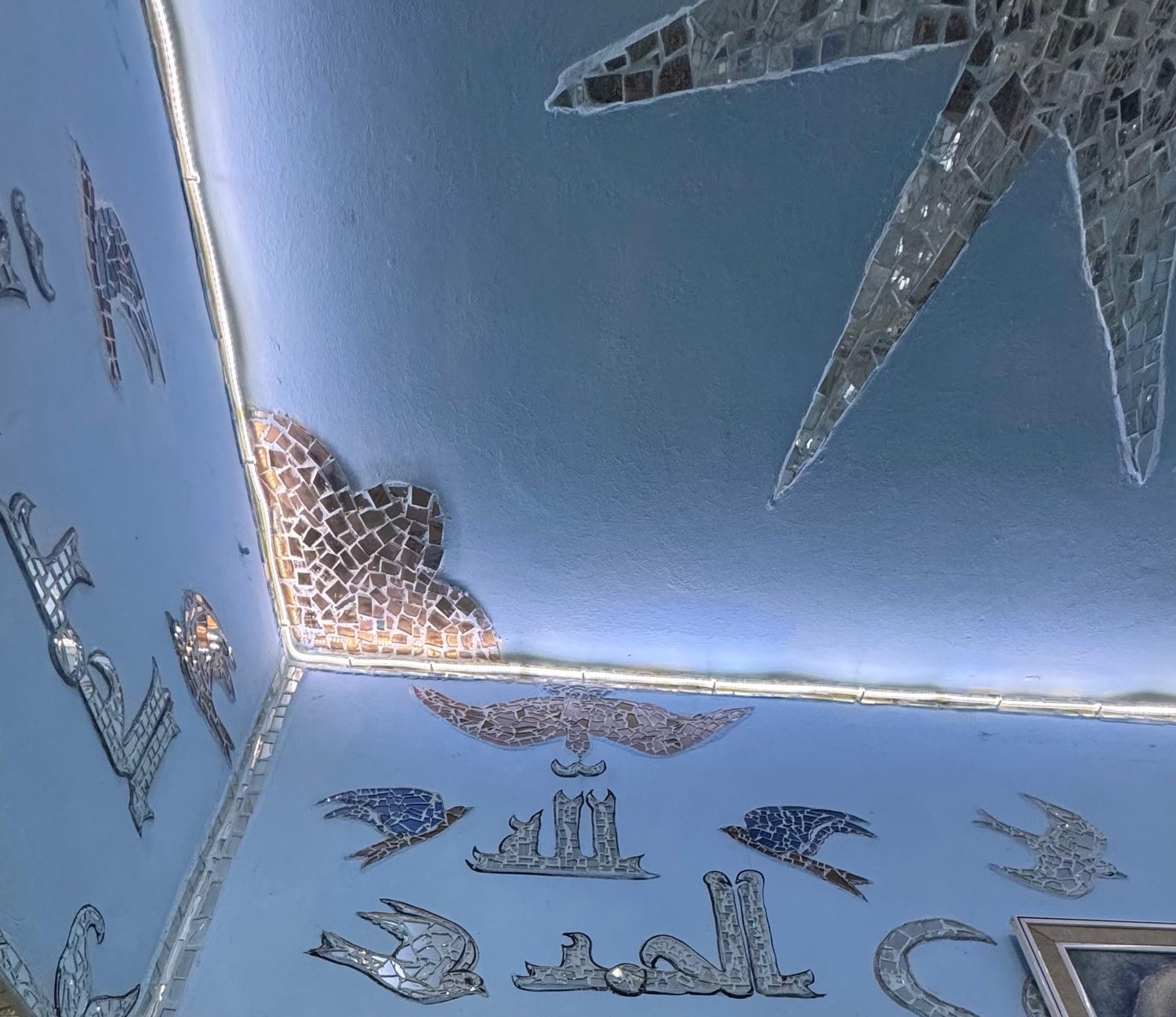 حمائم من فسيفساء المرايا وخطٌّ عربي على سقفٍ أزرق وزاويته